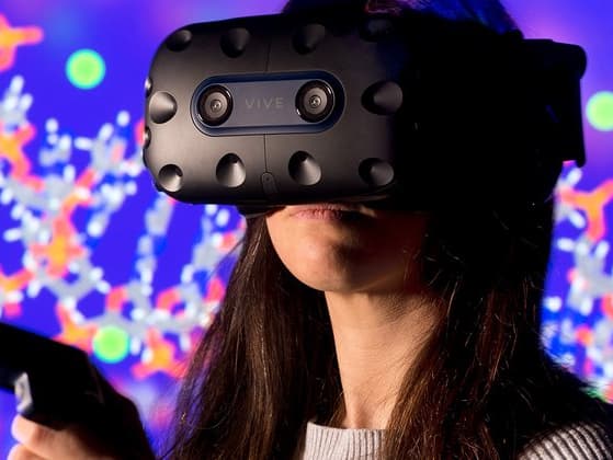 Osoba w goglach VR z kontrolerem przed kolorową wirtualną sceną