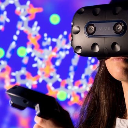 Osoba w goglach VR z kontrolerem przed kolorową wirtualną sceną