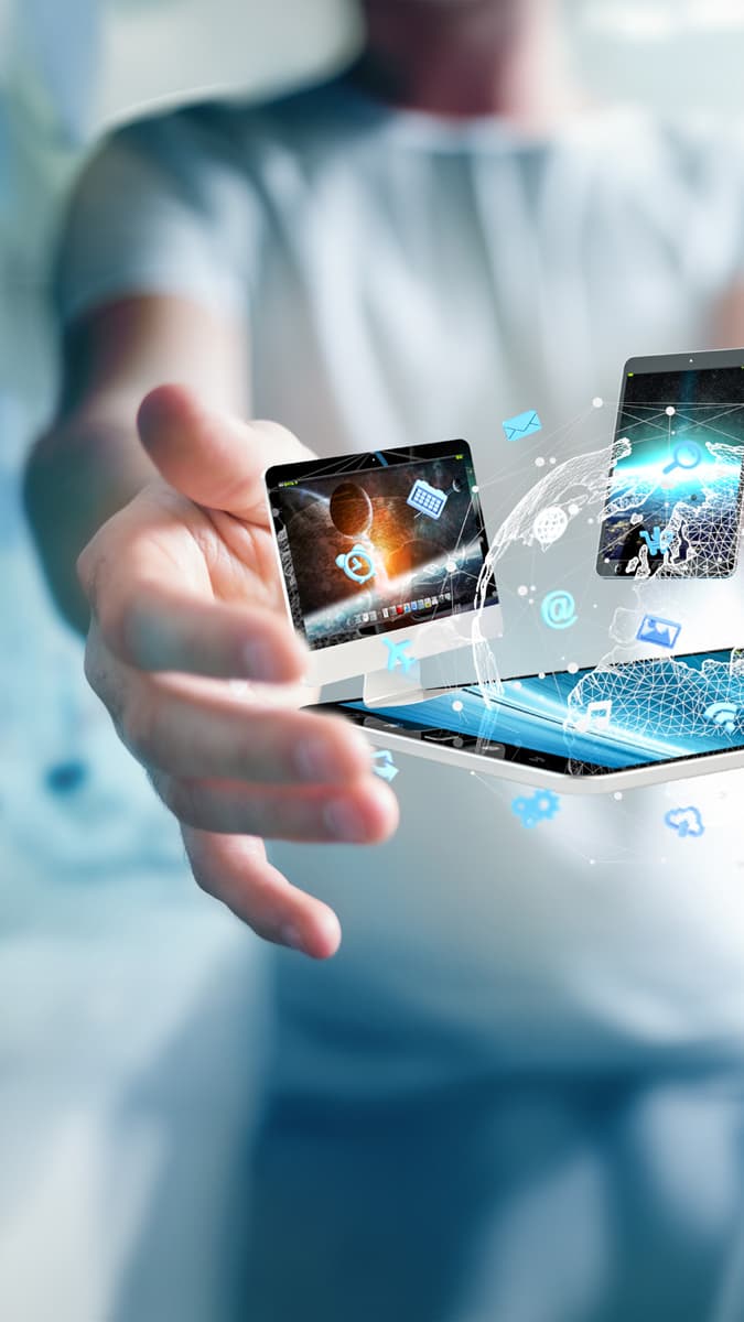 Unified Endpoint Management: Person präsentiert Tablet, Smartphone und Laptop in vernetzter Umgebung.