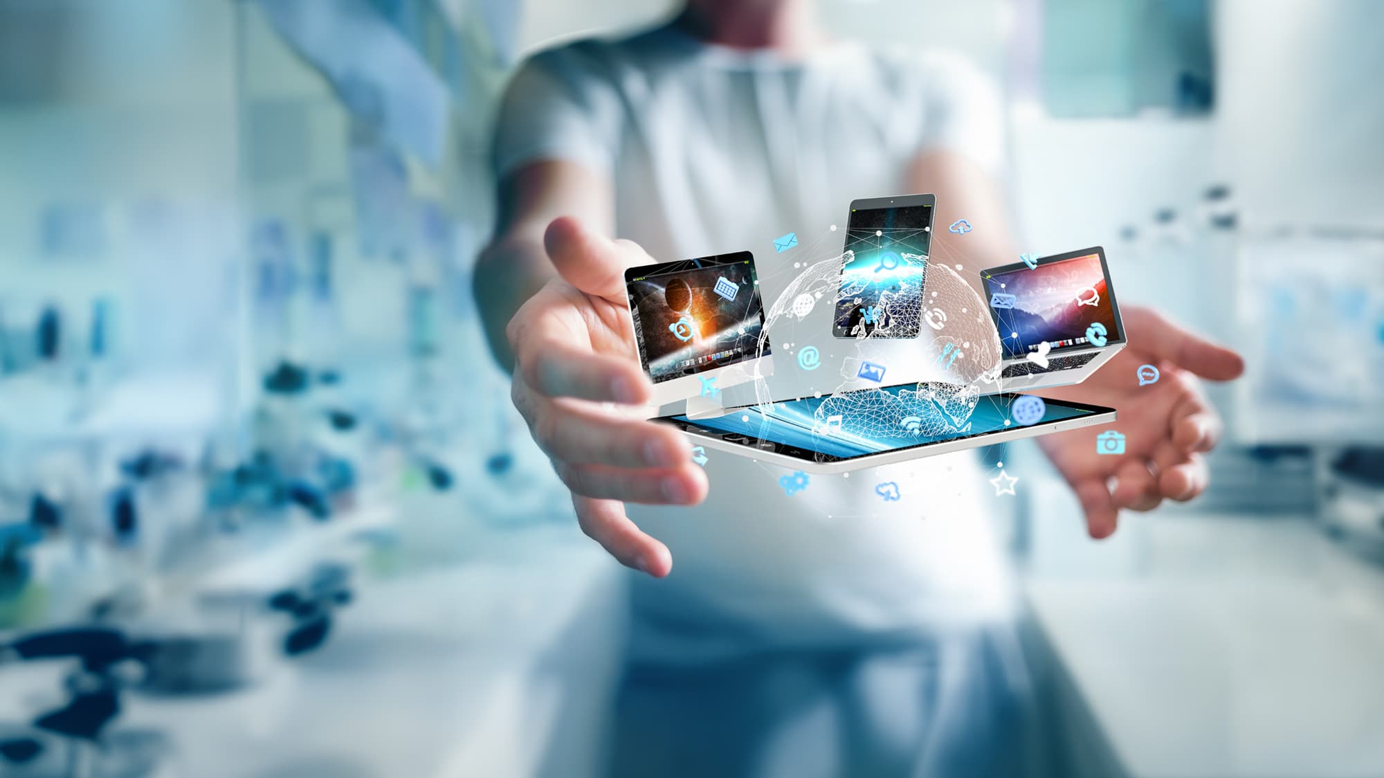 Unified Endpoint Management: Person präsentiert Tablet, Smartphone und Laptop in vernetzter Umgebung.