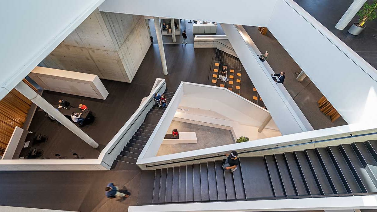 Nowoczesne atrium biurowe z kilkoma klatkami schodowymi, miejscami do siedzenia i ludźmi