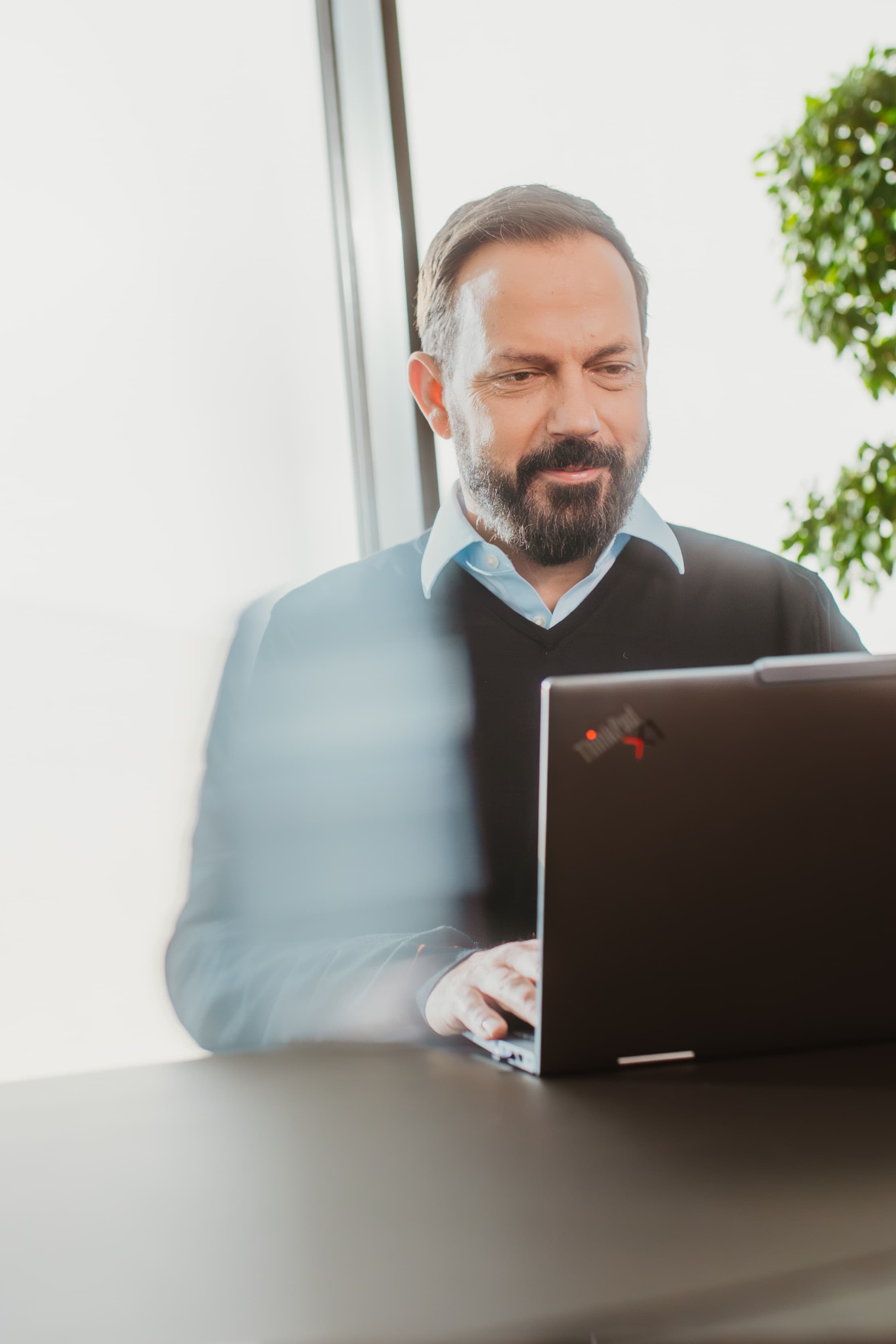 IT-Management: Mitarbeiter arbeitet im Konferenzraum an einem Laptop.