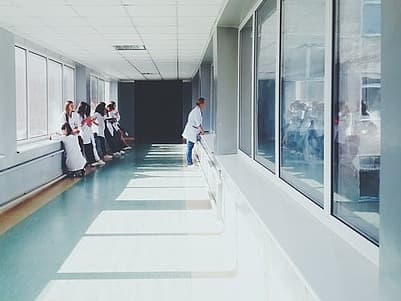 A bright hallway with several people in white lab coats and large windows