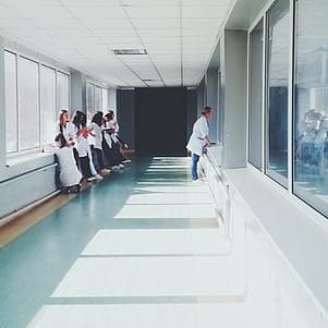 A bright hallway with several people in white lab coats and large windows