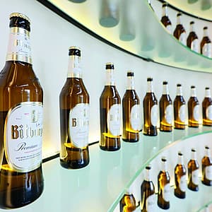 Bottiglie di Bitburger Premium Pils su scaffali di vetro ricurvi