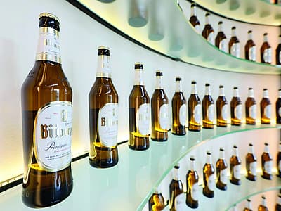 Bottiglie di Bitburger Premium Pils su scaffali di vetro ricurvi