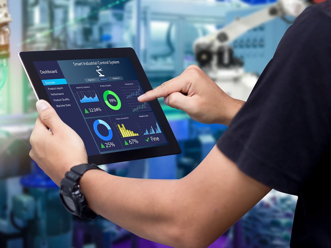 Person bedient ein Tablet mit Dashboard neben einem Industrieroboter.