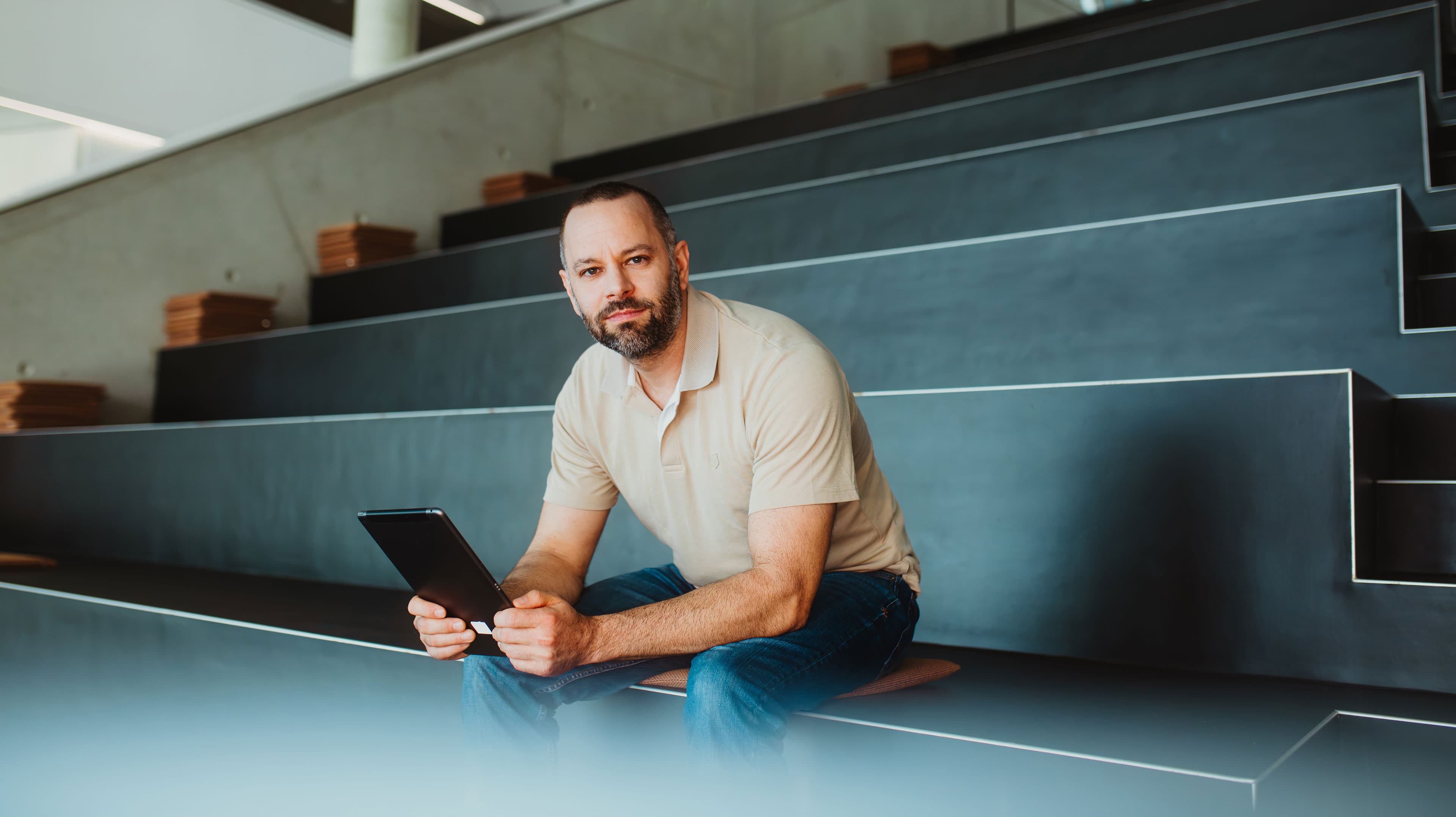 Mitarbeiter mit Tablet im Hörsaal – mobile Geräteverwaltung im Arbeitsalltag