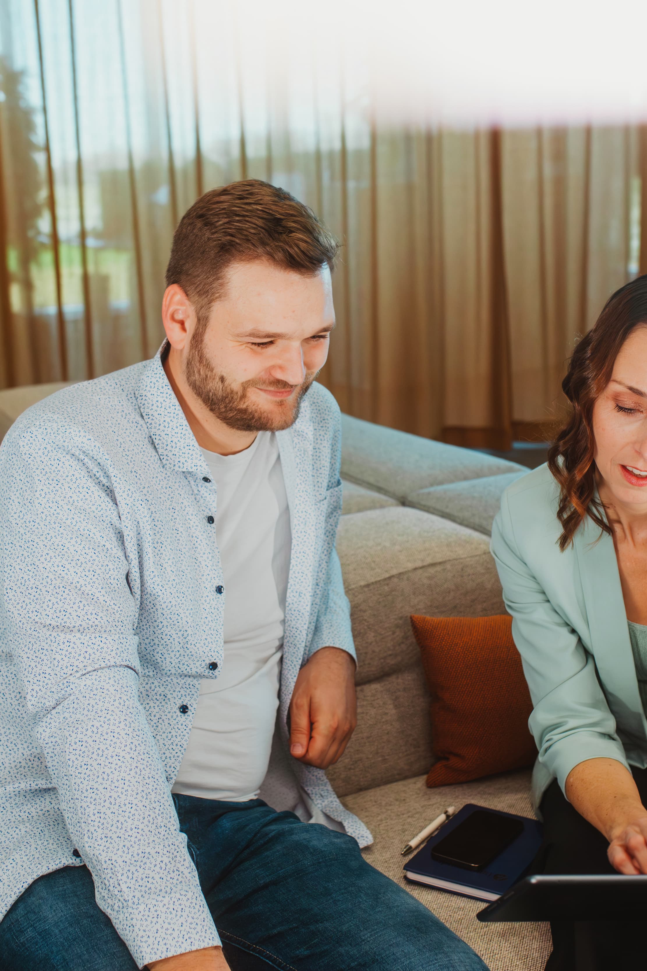 Two people are discussing a project using a tablet in a modern lounge