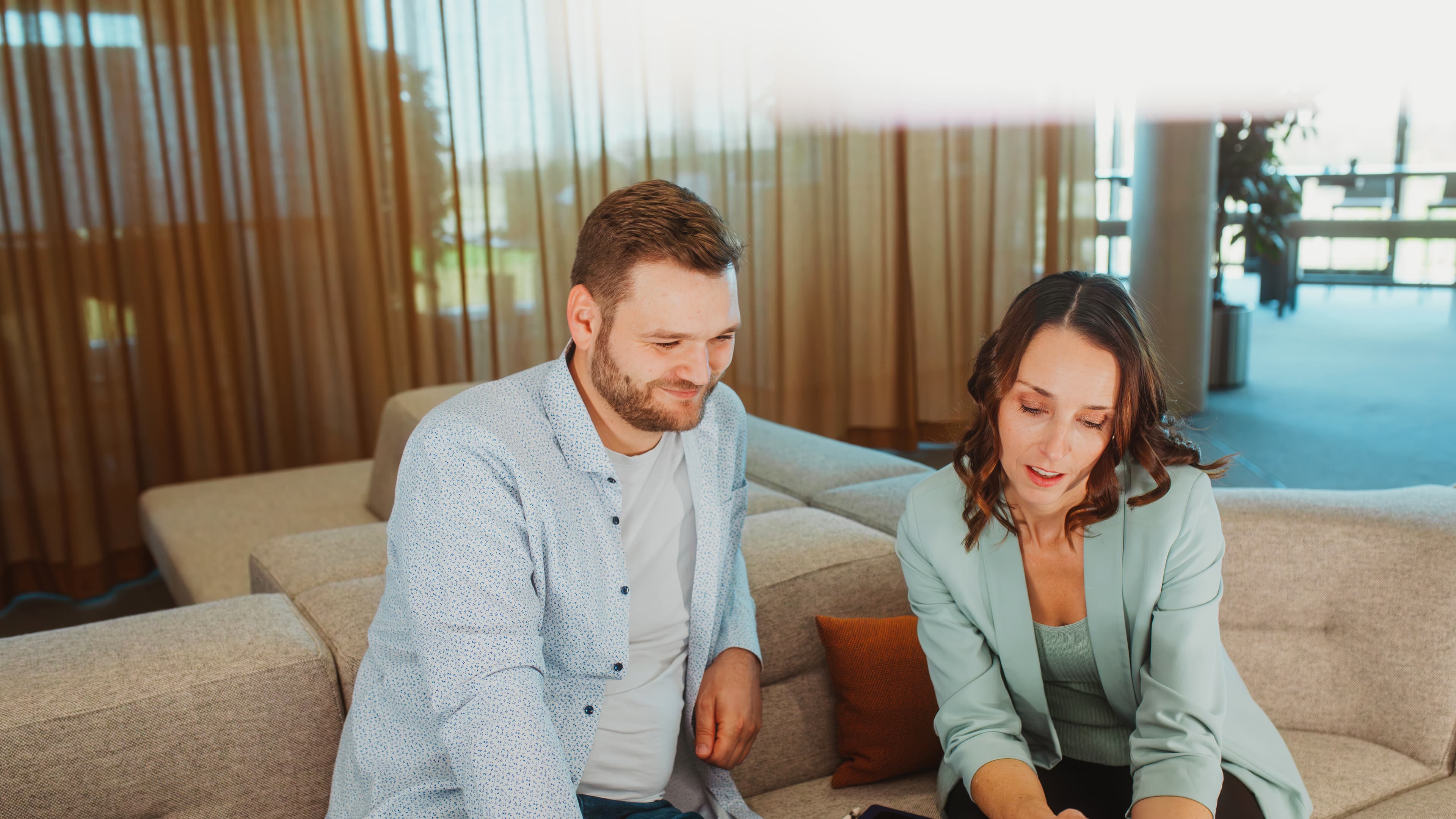 Two people are discussing a project using a tablet in a modern lounge