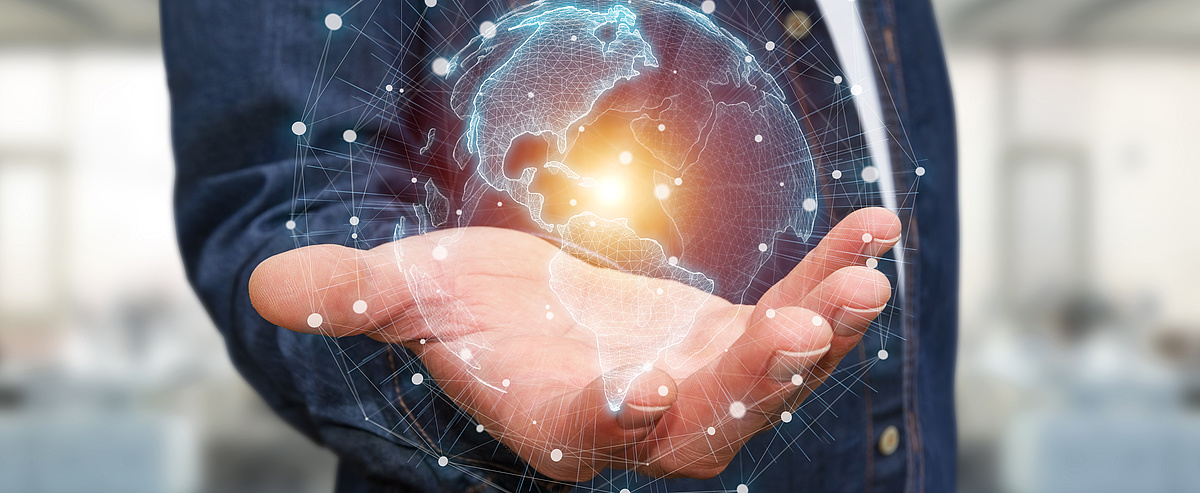 Abbildung einer Hand, die ein digitales Abbild der Erde mit verbundenen Netzwerken hält
