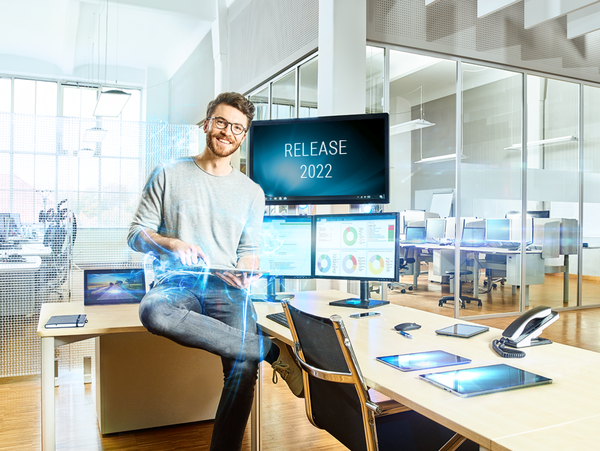 Mann im Technologiebüro vor Bildschirmen mit Release-Ankündigung "Release 2022"