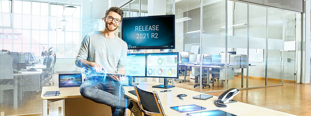Mann im Technologiebüro vor Bildschirmen mit Release-Ankündigung