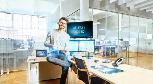 Mann im Technologiebüro vor Bildschirmen mit Release-Ankündigung "Release 2020 R2"