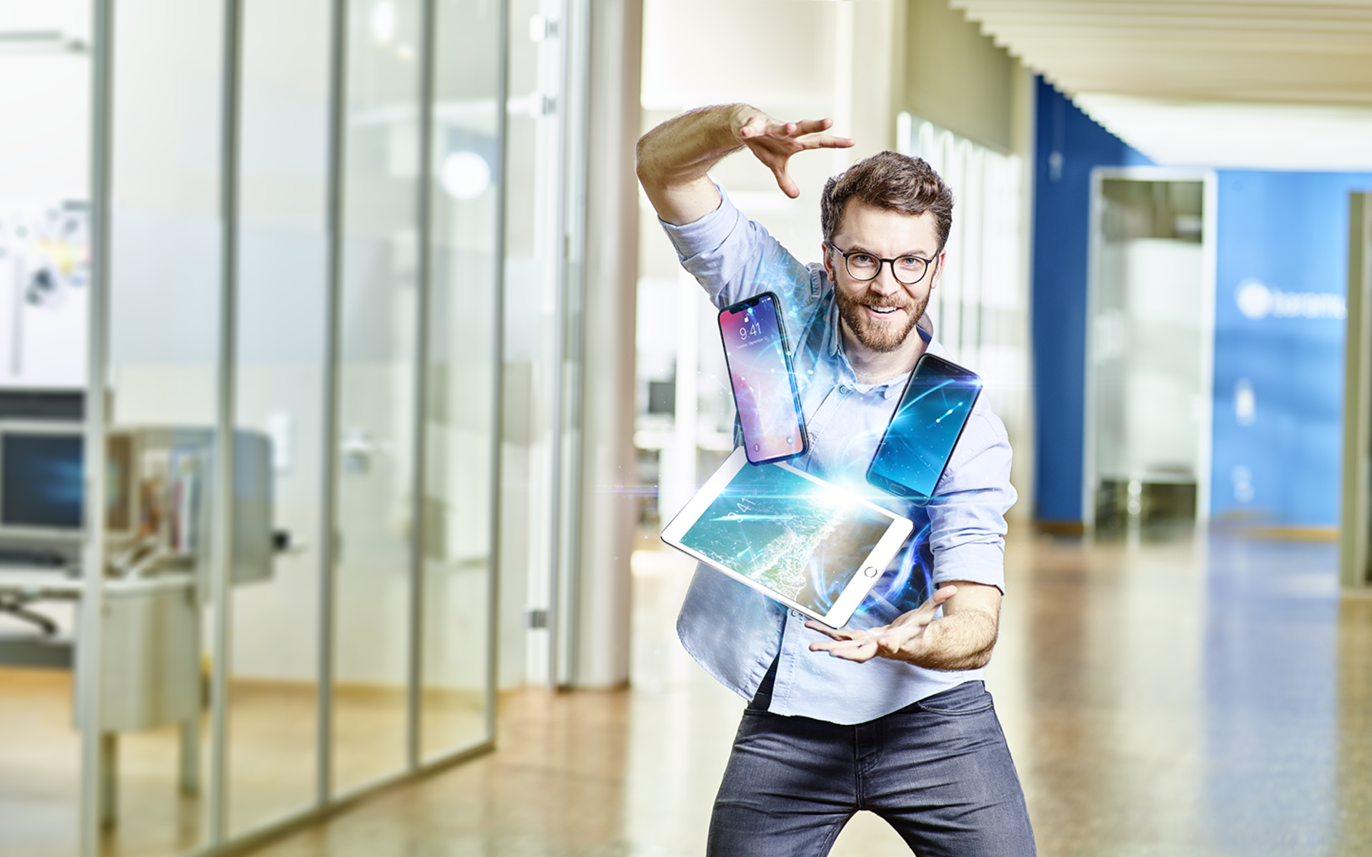 Ein fröhlicher Mann, der mehrere mobile Geräte mühelos in der Luft jongliert, um Enterprise Mobility Management zu demonstrieren