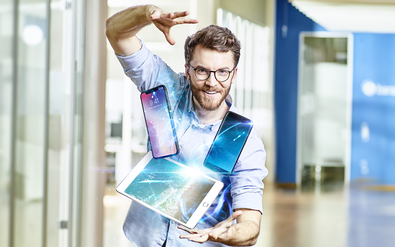 Ein fröhlicher Mann, der mehrere mobile Geräte mühelos in der Luft jongliert, um Enterprise Mobility Management zu demonstrieren