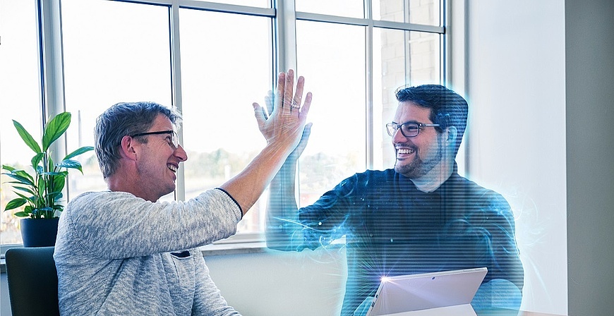 Mann mit Brille im Büro gibt High-Five mit holografischer Figur