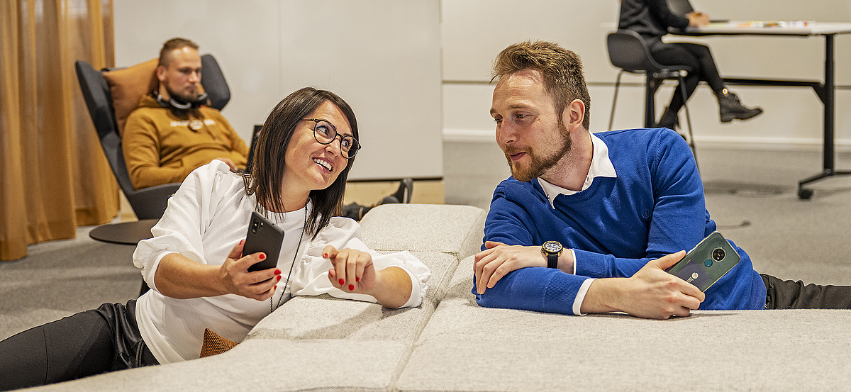 baramundi Mitarbeiter tauschen sich entspannt in der Lounge über ihre Mobilgeräte aus