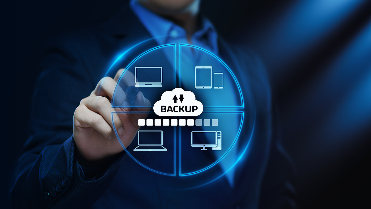 Ein professionell gekleideter Geschäftsmann zeigt auf ein digitales Diagramm, das eine Cloud-Backup-Lösung für verschiedene Geräte symbolisiert