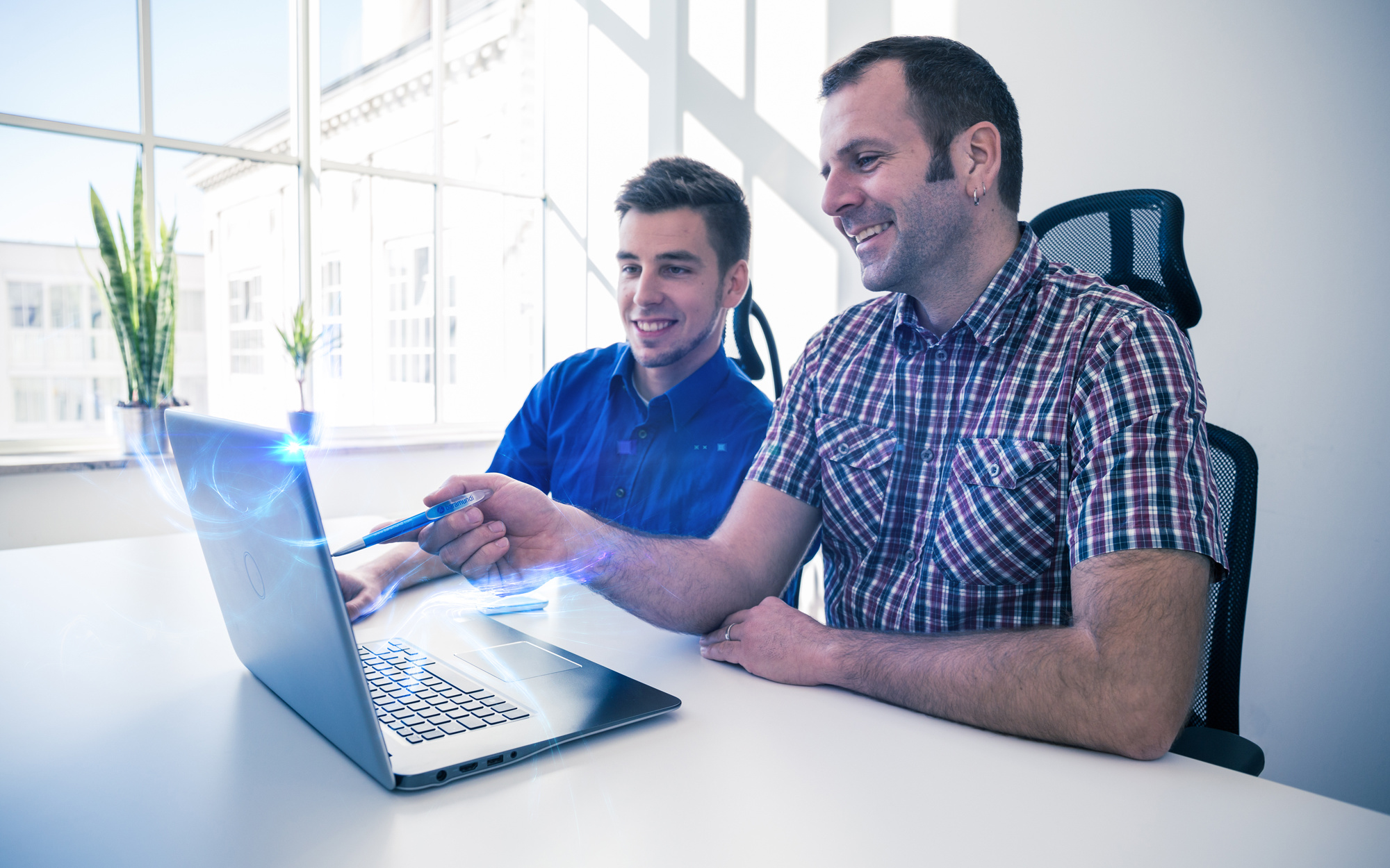 Zwei baramundi-Mitarbeiter arbeiten zusammen an einem Laptop in einem modernen Büro